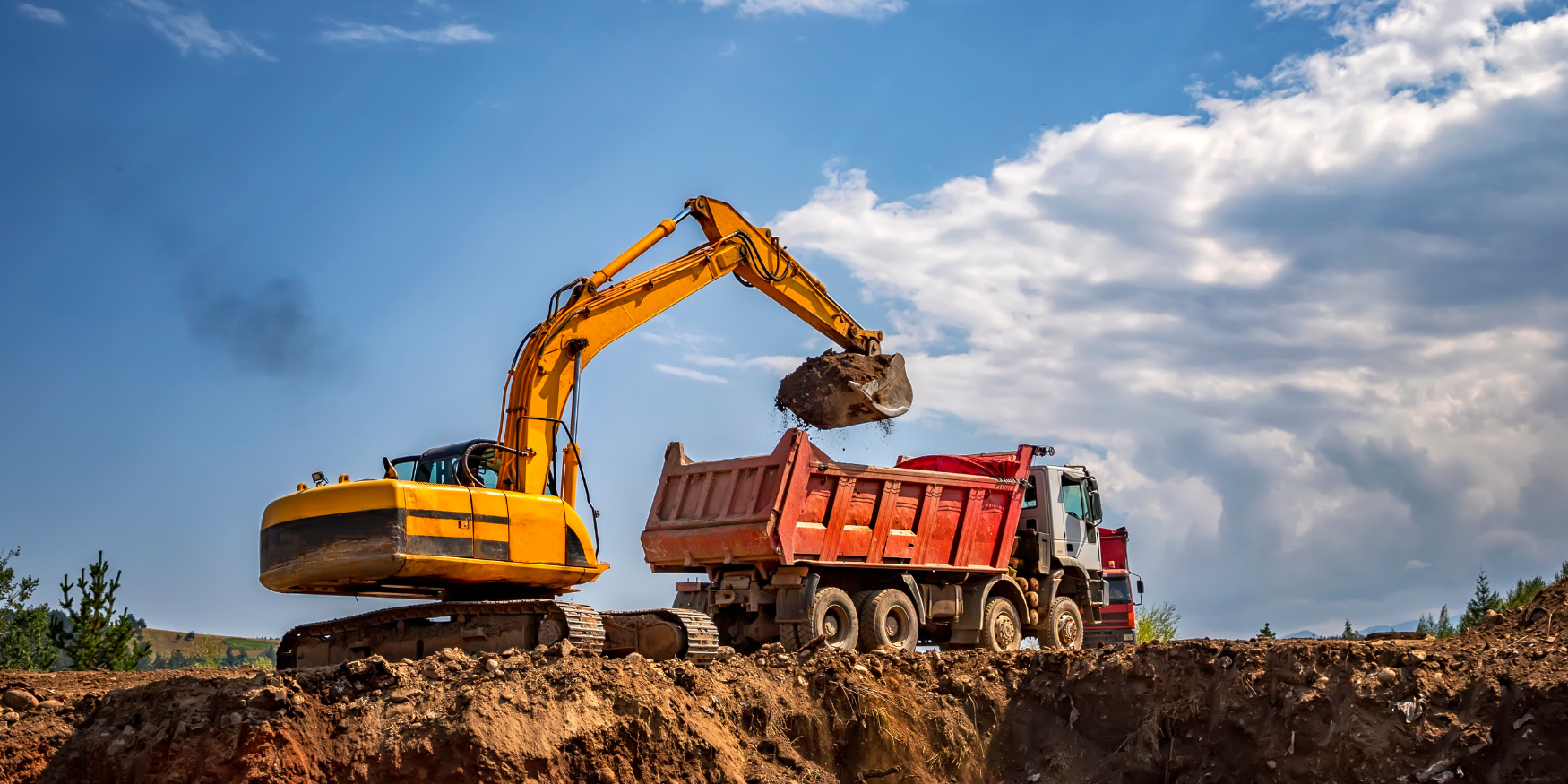 A dump truck and a construction vehicle on a dirt hill